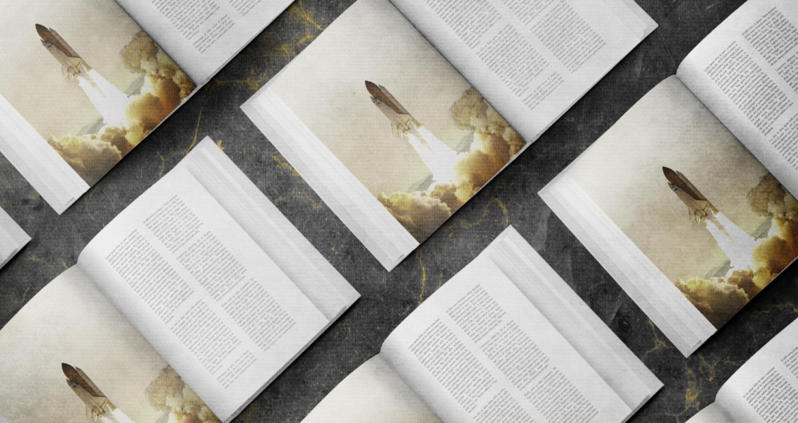 Open magazines are laid out in a grid pattern on a dark surface, featuring text and an image of a rocket launching amidst clouds.