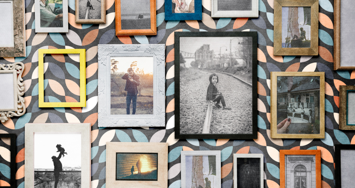 A wall covered with an array of framed photographs. The images depict various people, nature scenes, and objects. The frames have different designs, set against a geometric patterned wallpaper.